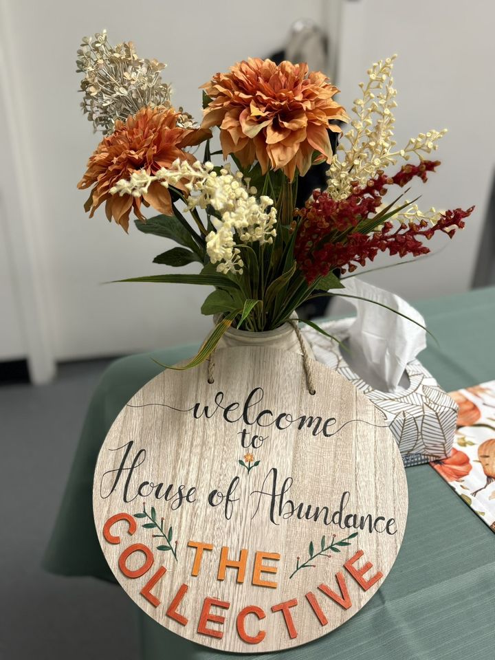 A wooden sign reading Welcome to House of Abundance, beside a bouquet of autumn flowers