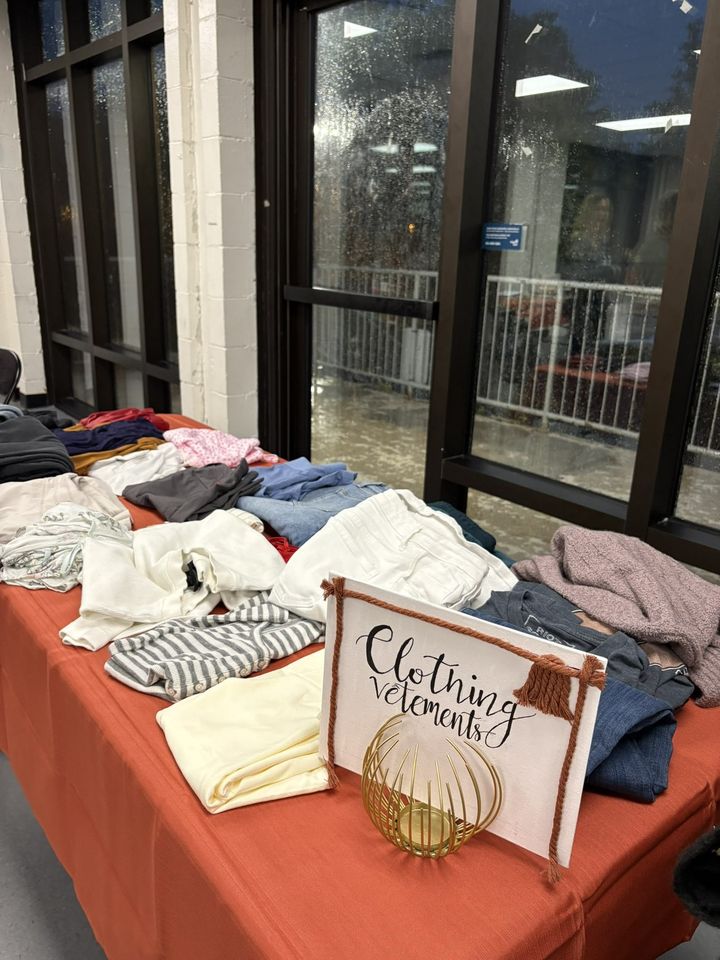 A table of folded clothing under a hand-lettered sign