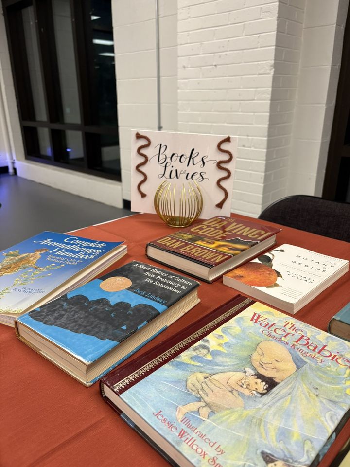Books laid out on a table under a hand-lettered sign