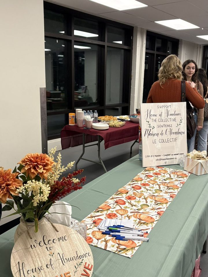 The welcome table, with flowers and the House of Abundance sign